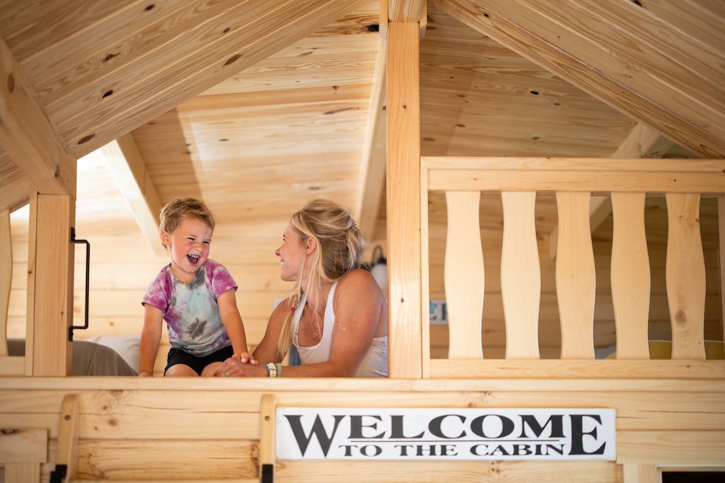 A woman and a child are playing in a wooden cabin.