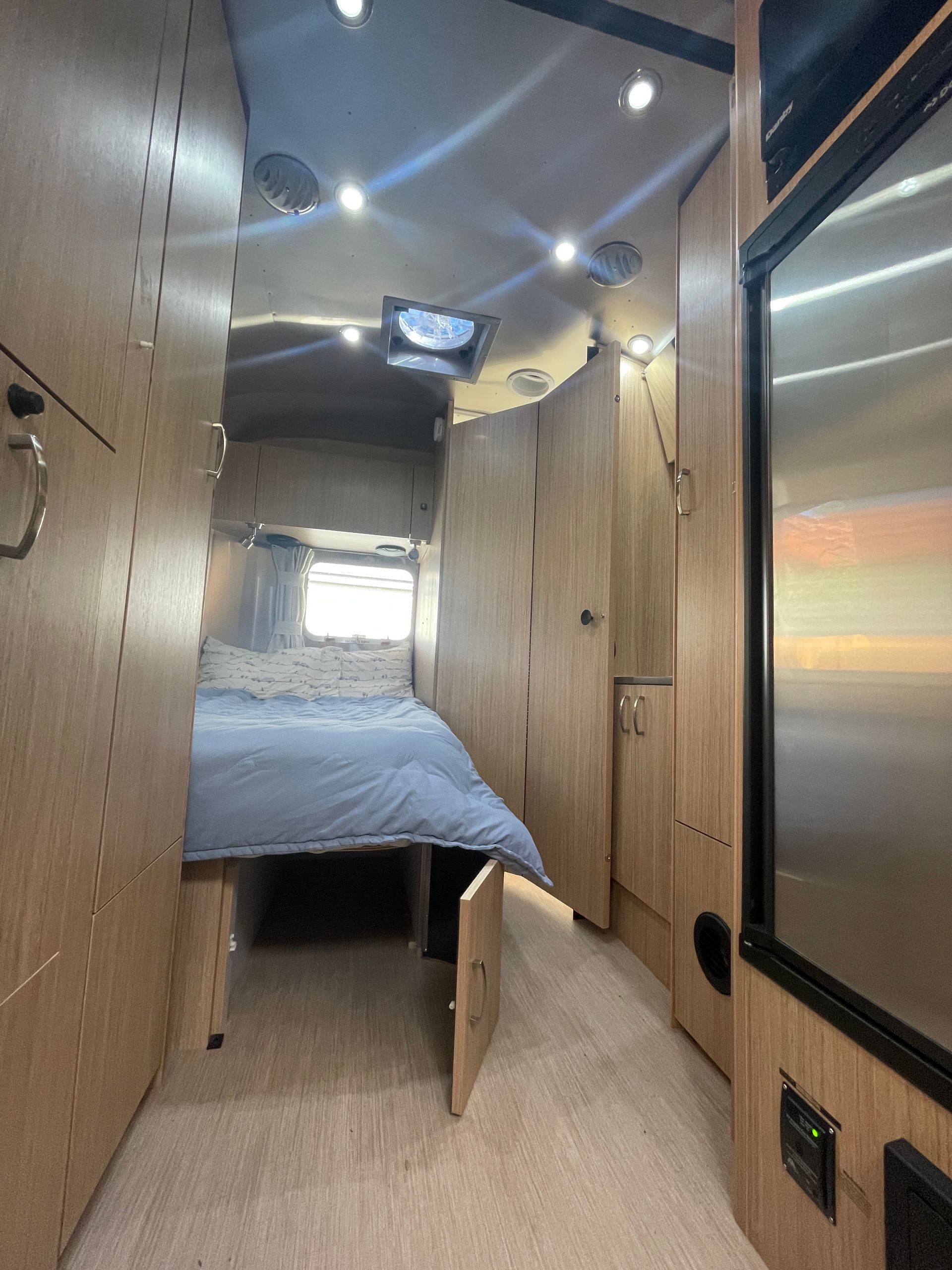 A bedroom with a bed and a stainless steel refrigerator