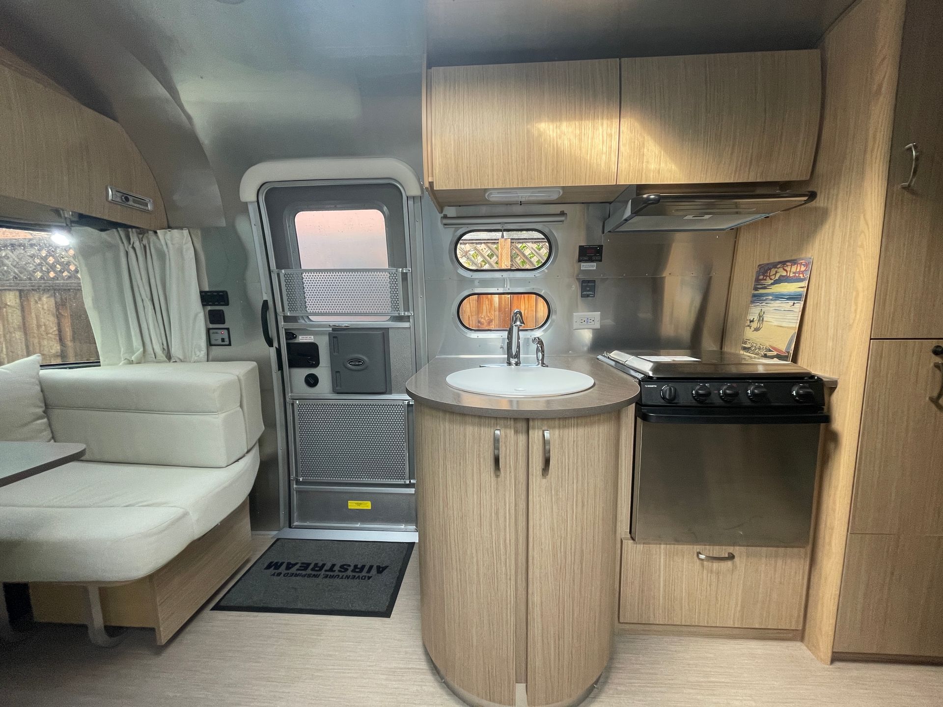 A kitchen in an airstream trailer with wooden cabinets and stainless steel appliances.