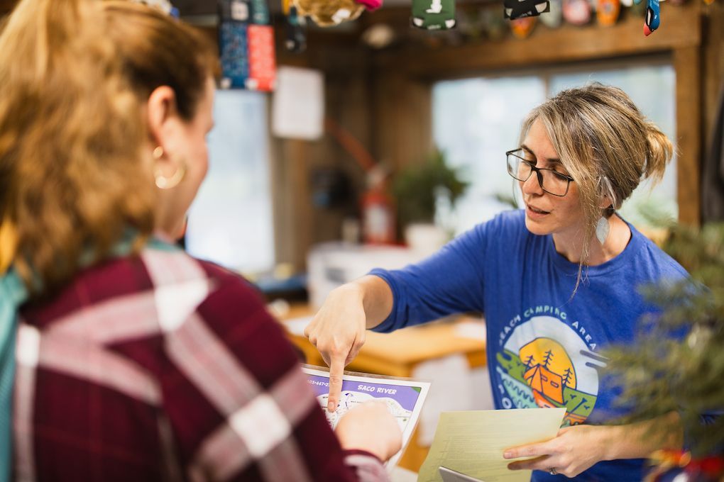 A woman is pointing at a piece of paper while talking to another woman.