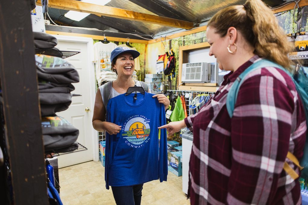 Two women are standing in a store looking at a blue shirt.