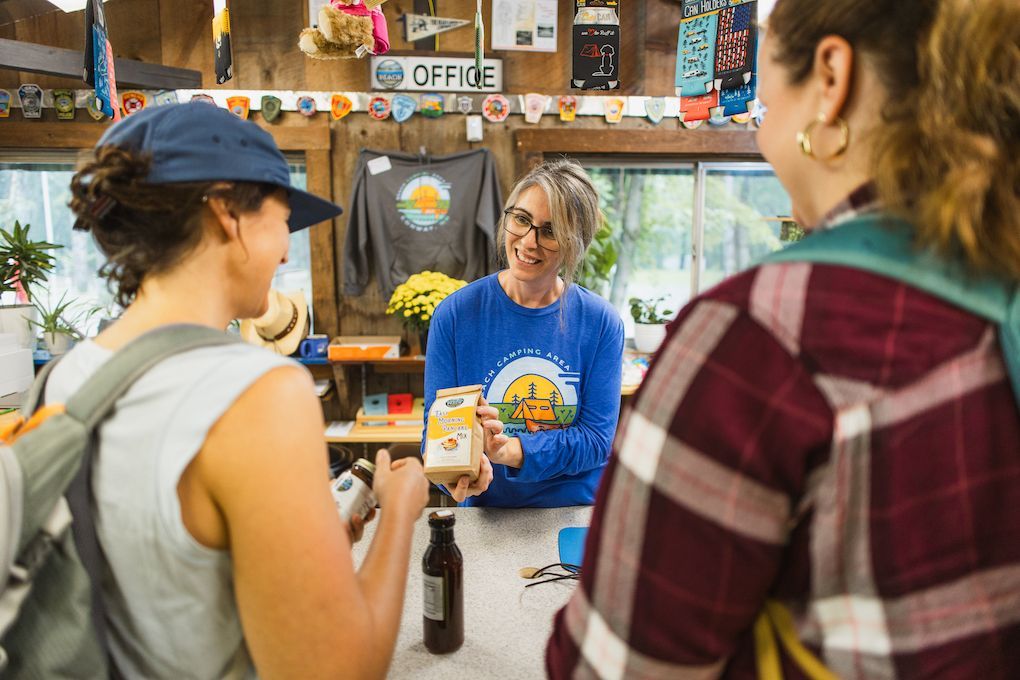 A woman is talking to two women at a counter in a store.