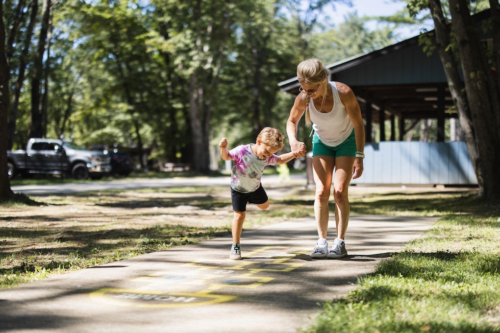 A woman and a little girl are running on a sidewalk.