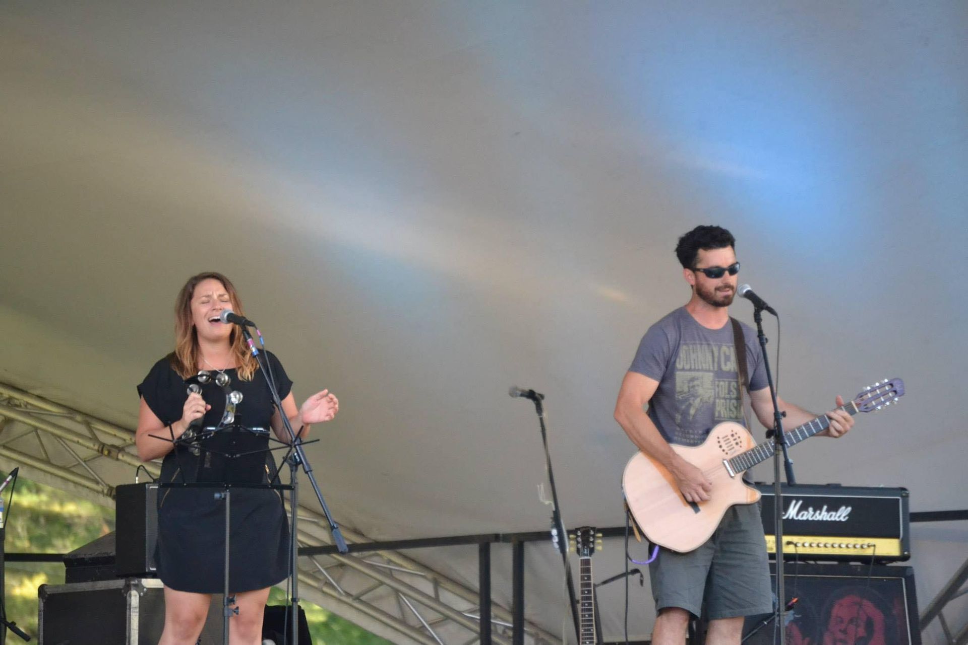 A man is playing a guitar while a woman sings into a microphone.