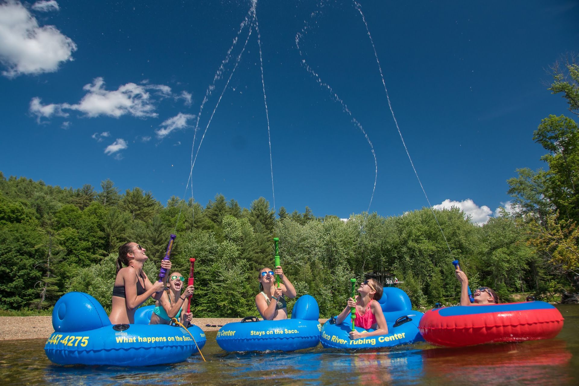 A group of people are sitting on inflatable rafts in a lake.