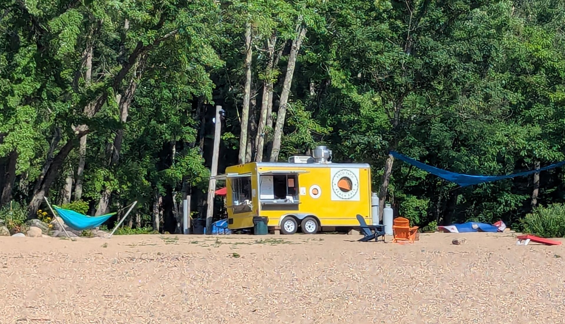 A yellow food truck is parked on the beach.