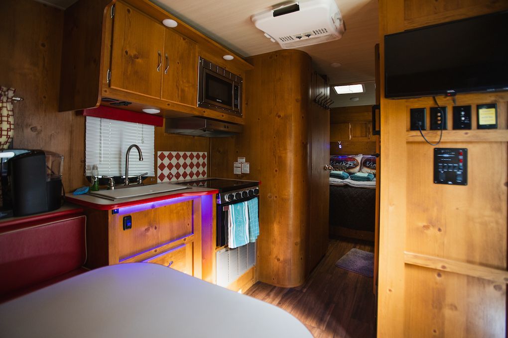A kitchen in a rv with a stove , sink , and television.