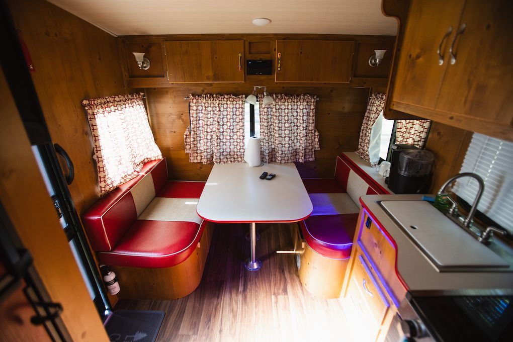 The inside of a trailer with a table and chairs and a sink.
