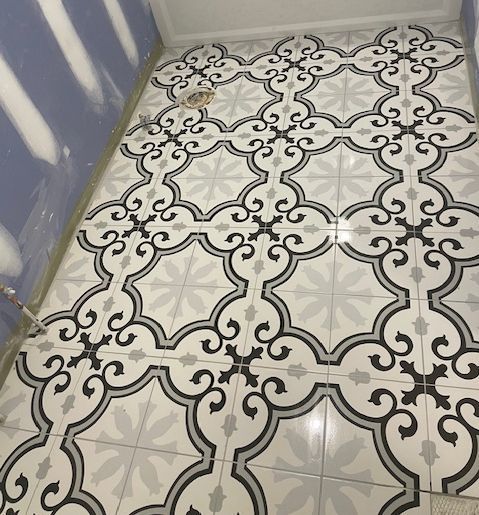 Decorative tile floor with gray and black floral pattern.