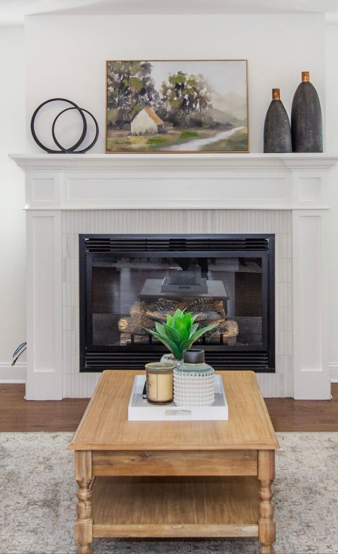 Fireplace with painting, decor, and wooden coffee table in front.