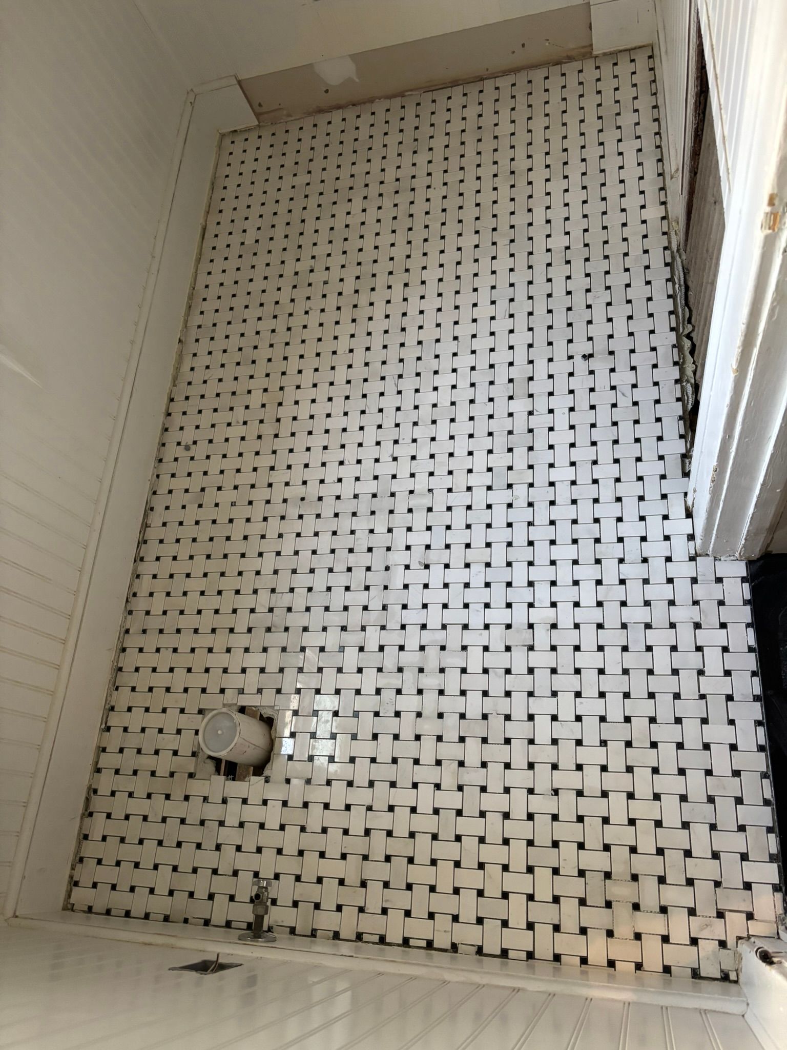 Bathroom floor tiled with black and white square pattern, unfinished.