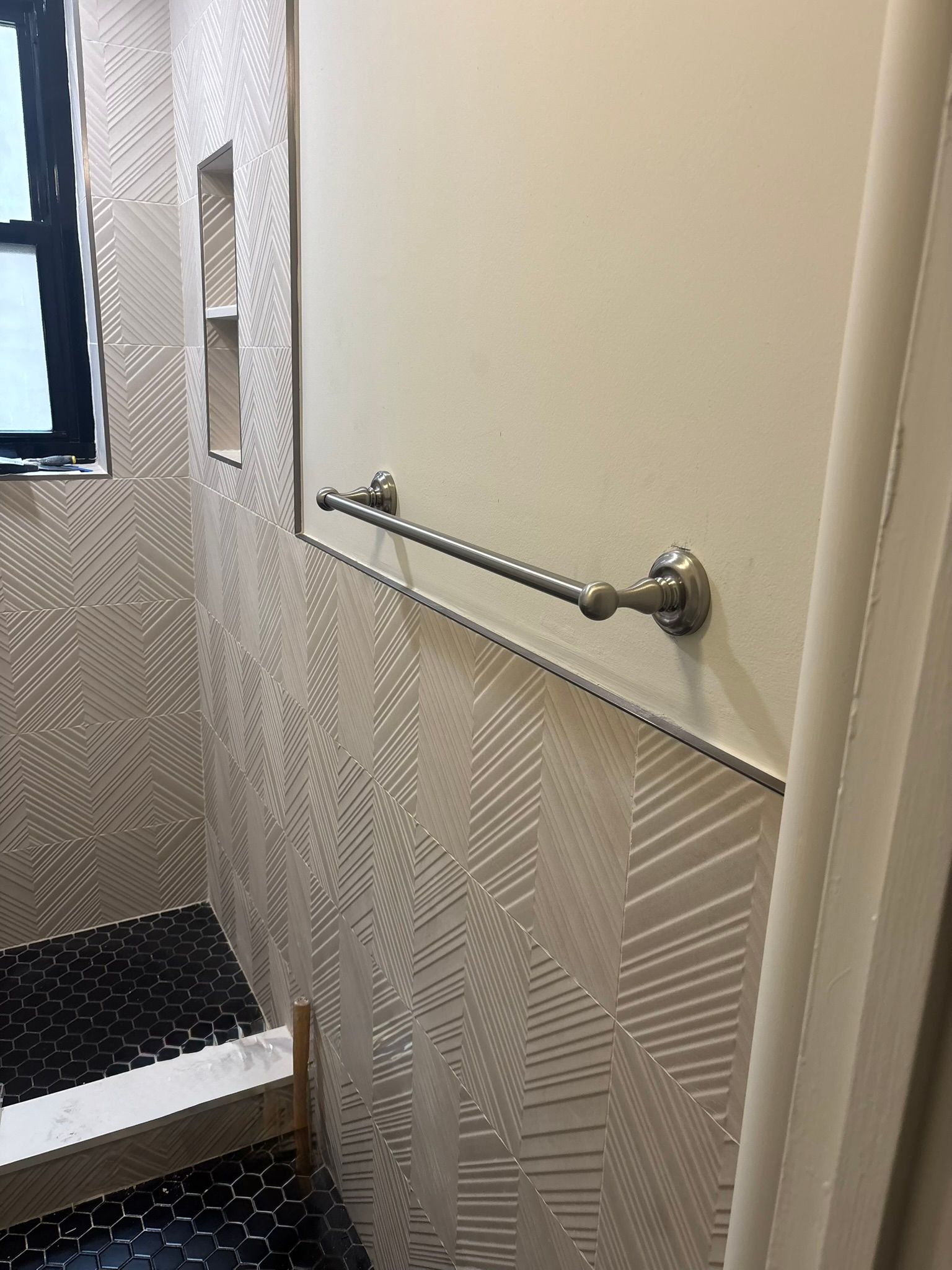 Bathroom with patterned tile walls, a towel rack, and a window.