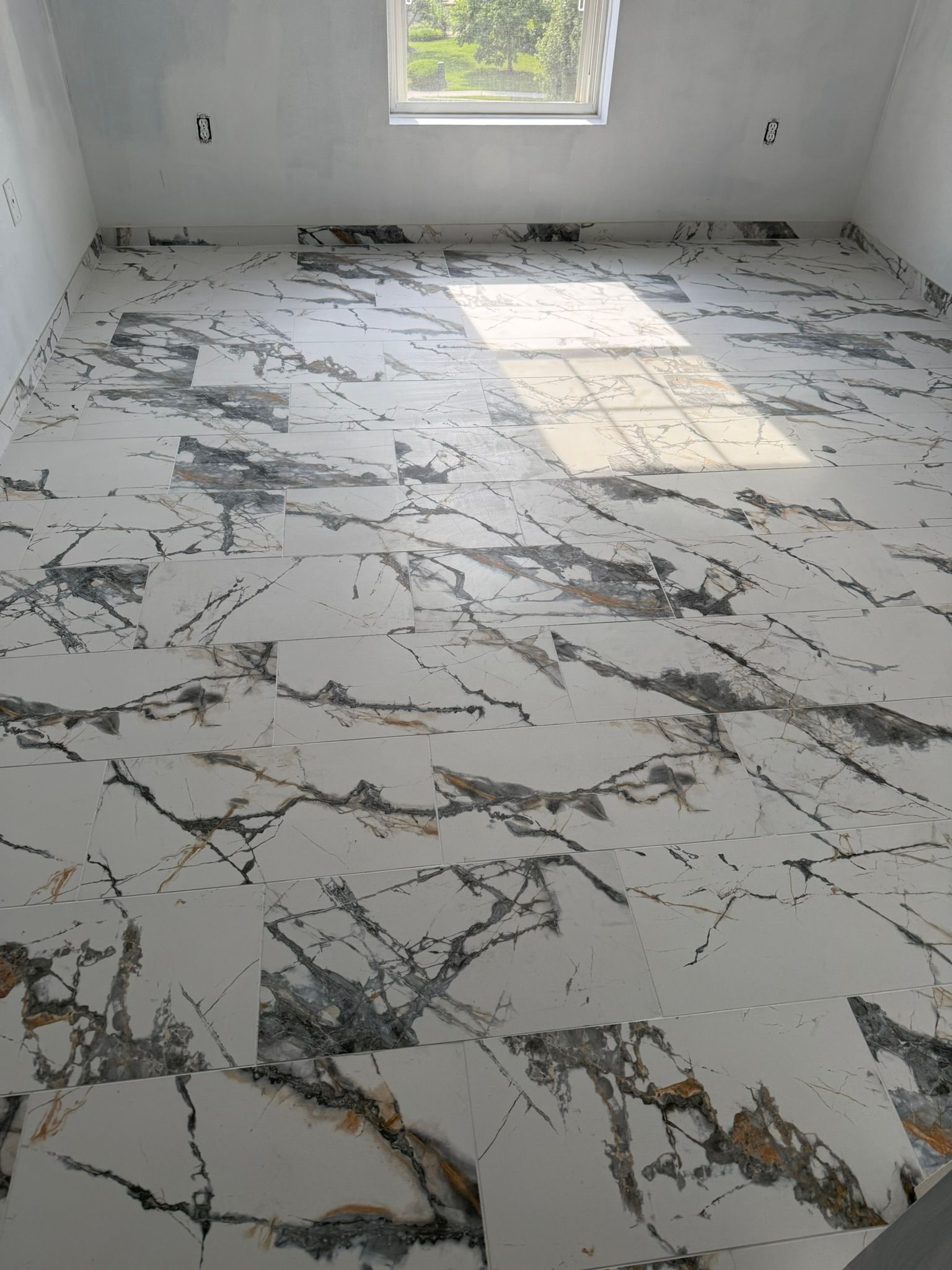 Room with marble-patterned flooring. Window at top, sunlight across floor.