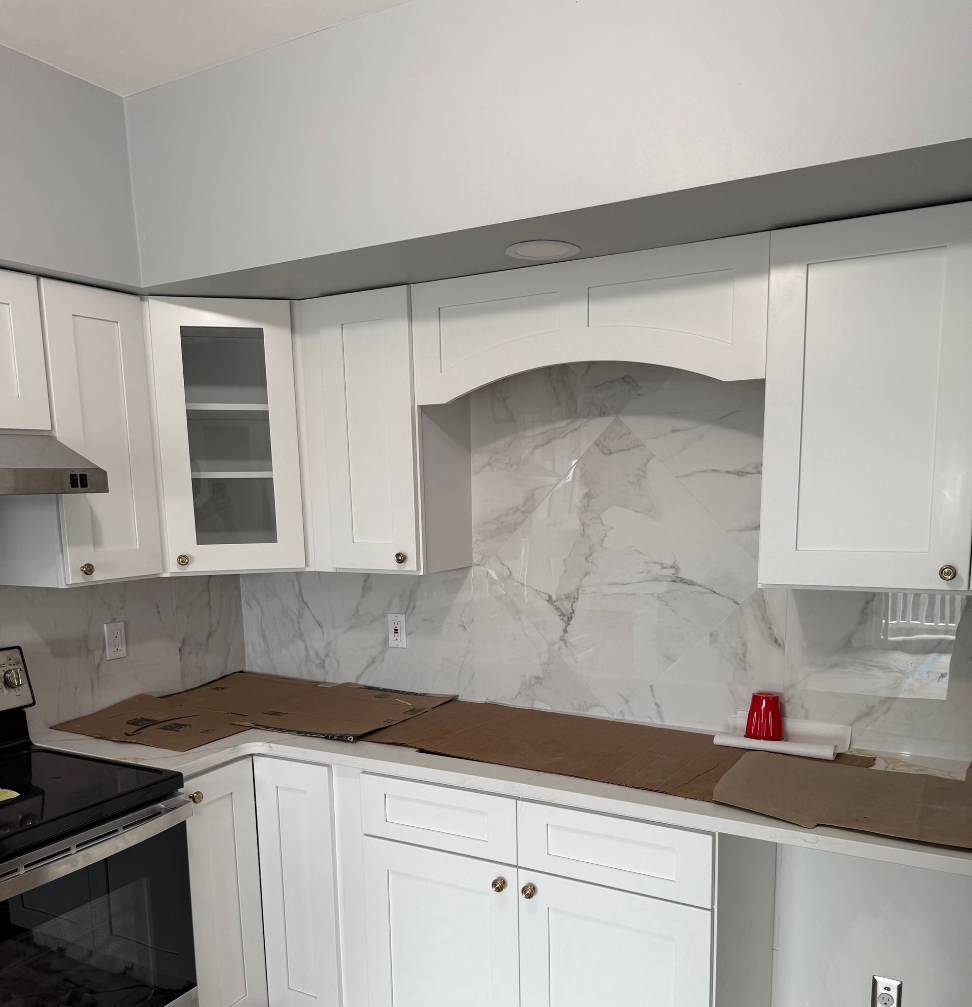 White kitchen cabinets, marble backsplash, brown countertops.