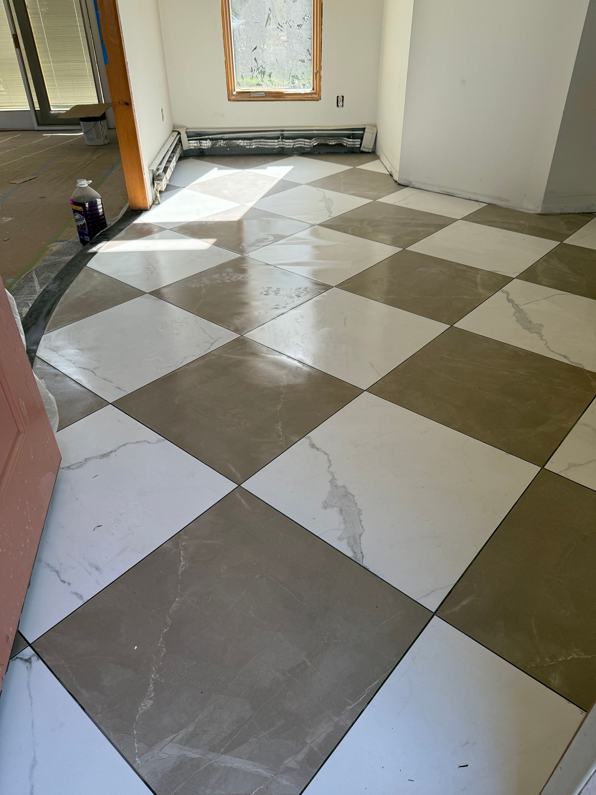 Checkerboard patterned floor with white and brown tiles. Room has window and open doorway.