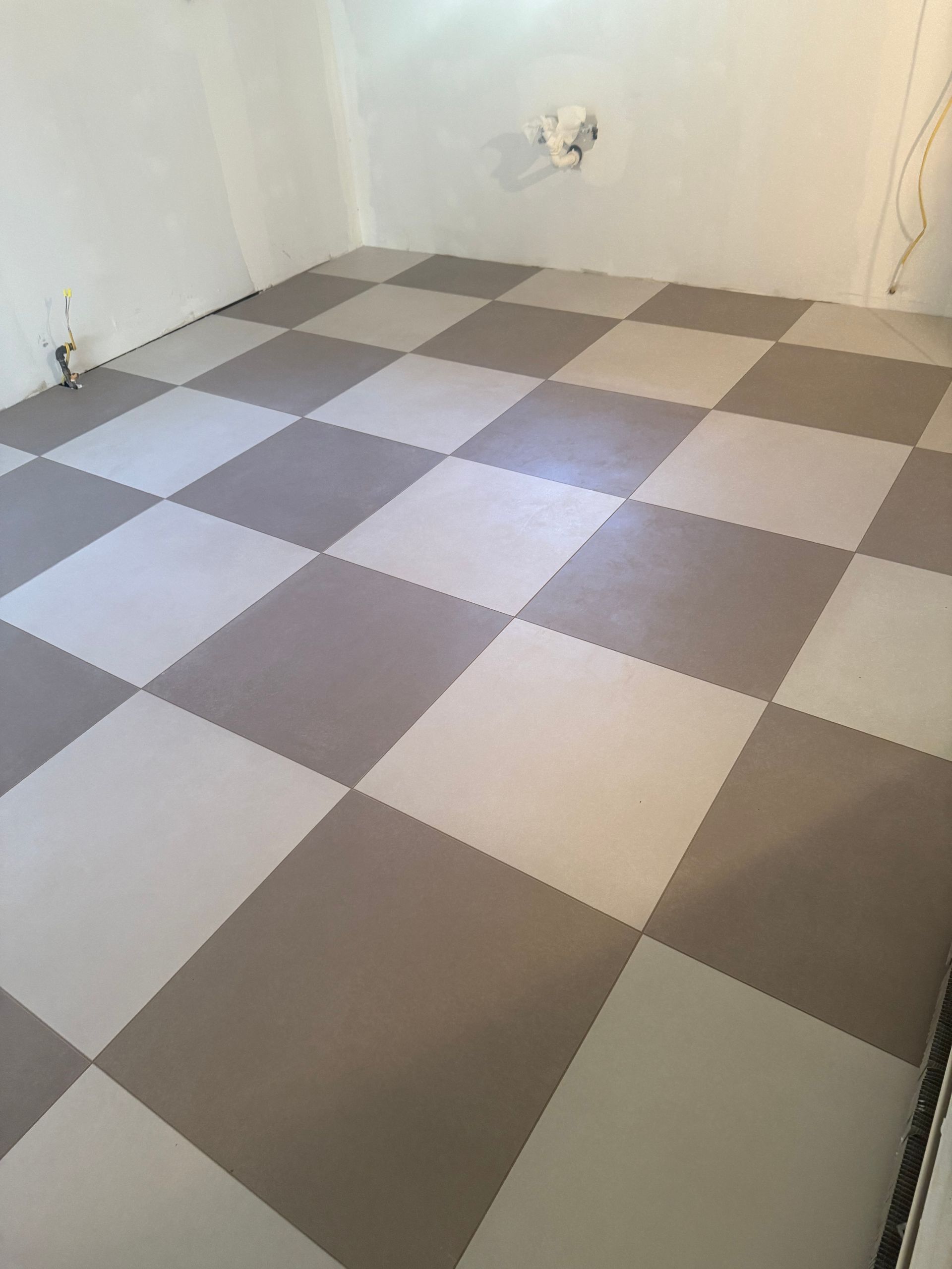 Checkerboard-patterned floor of gray and white tiles in a room with white walls.