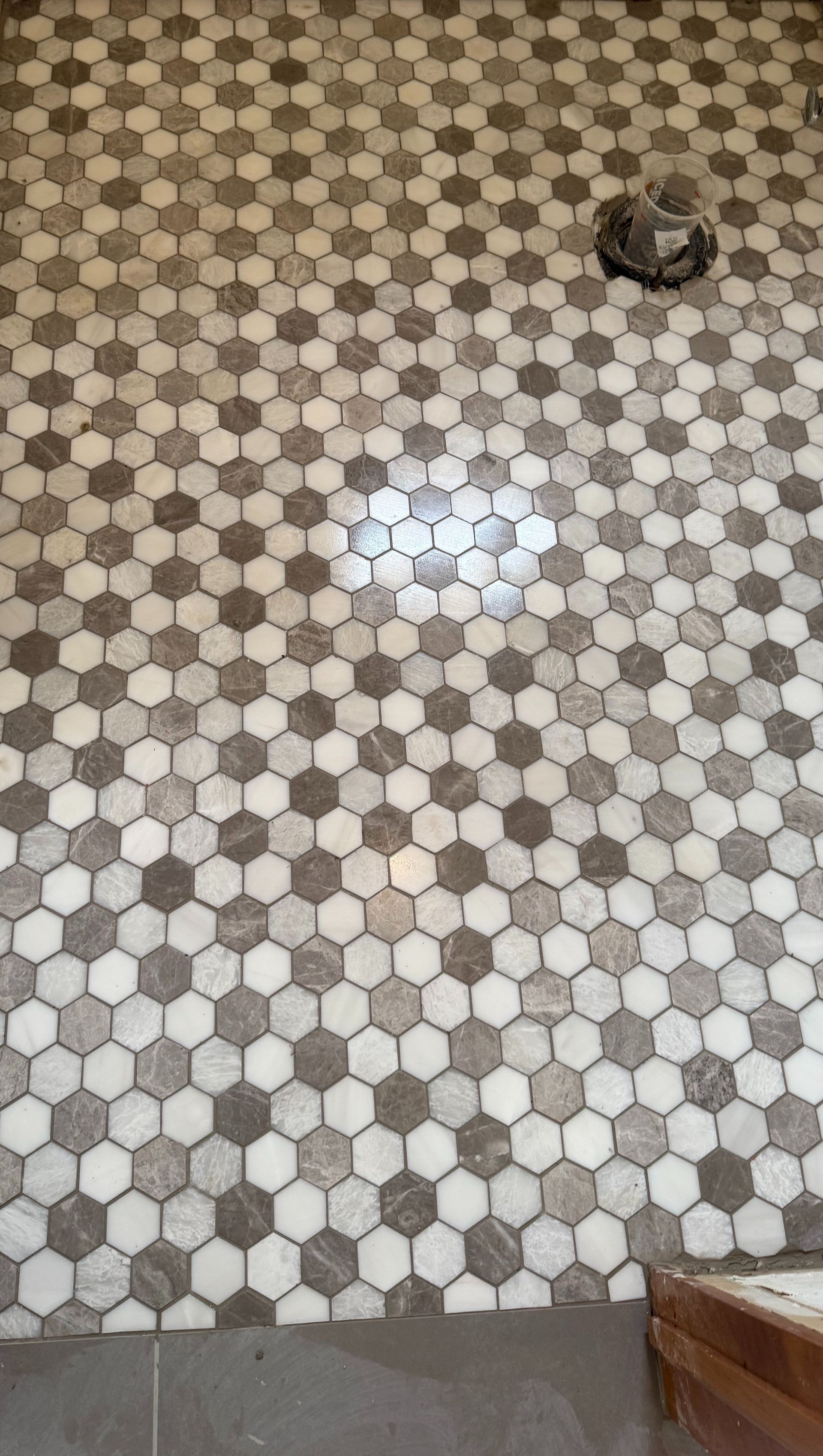 Gray and white hexagon mosaic tile wall with plumbing fixtures.