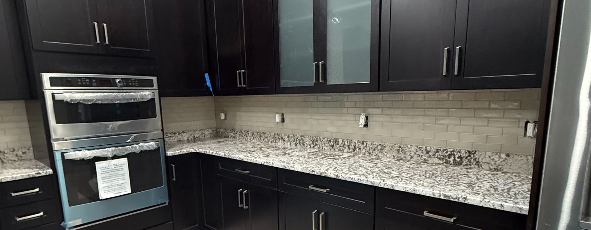 Kitchen with dark cabinets, granite countertops, and a stainless steel oven.