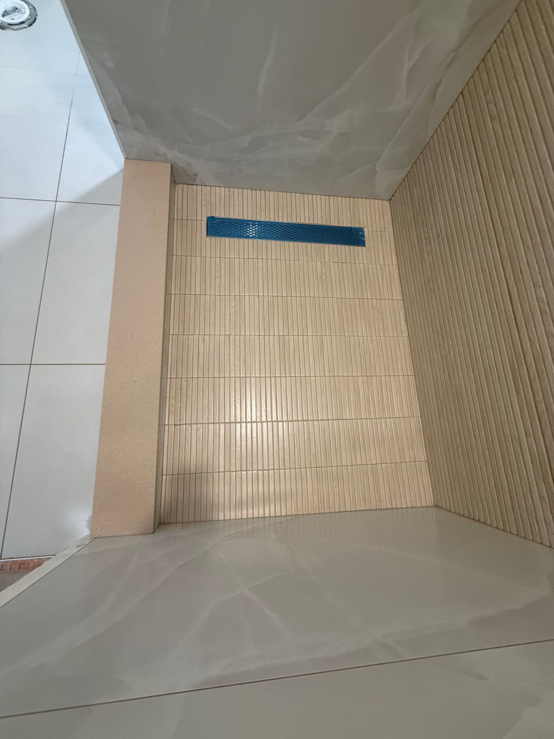 Interior view of a room with light wood paneling, a concrete floor, and a blue-covered vent.