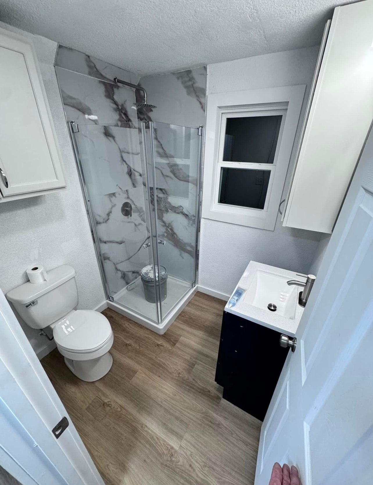 A bathroom with a toilet , sink , shower and window.