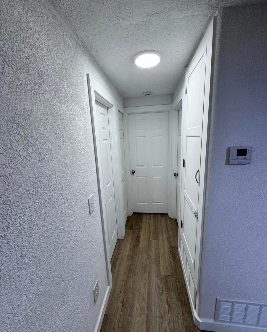 A long hallway with white walls and wooden floors in a house.