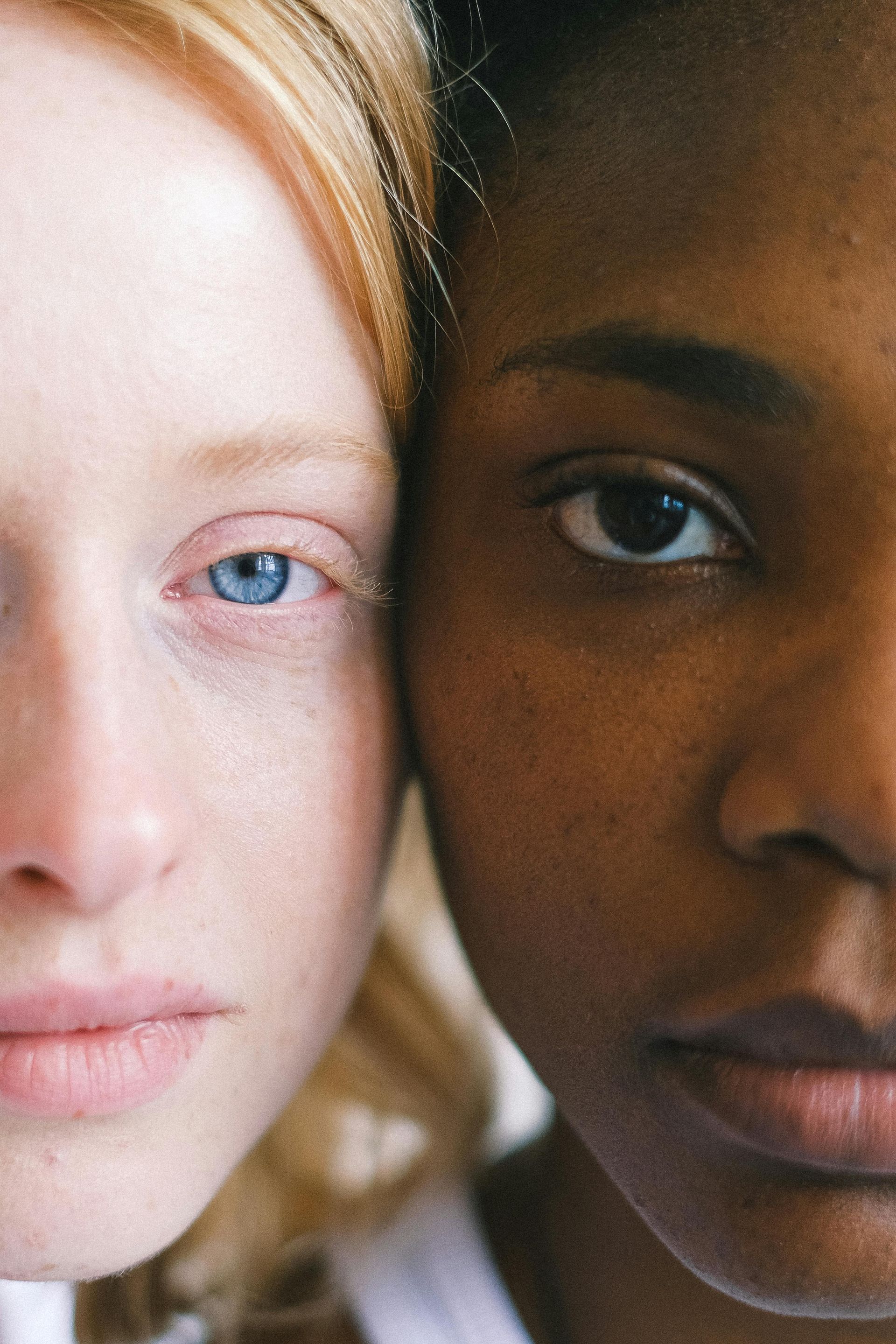 Two women , one white and one black , are standing next to each other and looking at the camera.