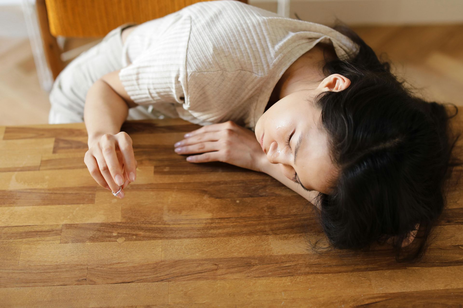 A woman is laying on the floor next to a wooden table.