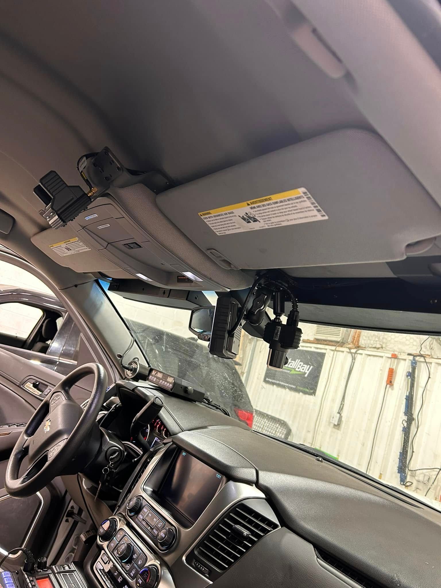 Interior view of a vehicle with a sun visor and mounted gun holsters above the dashboard.