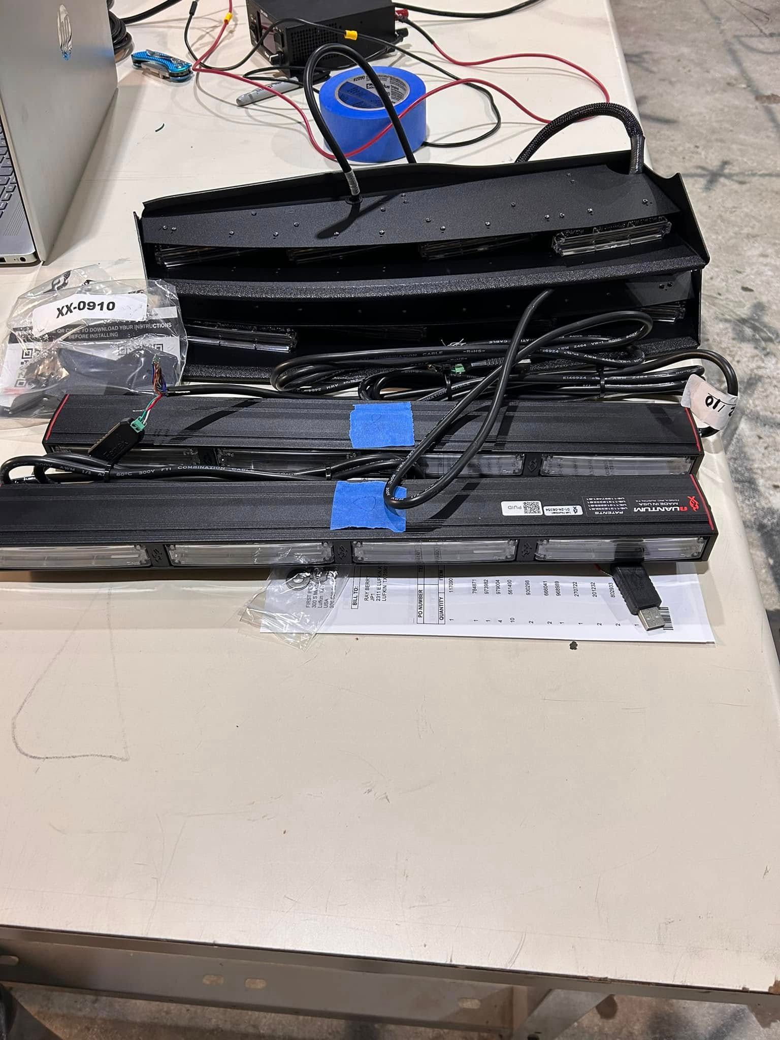 Overhead emergency vehicle light bars on a table, with wiring and a power supply.