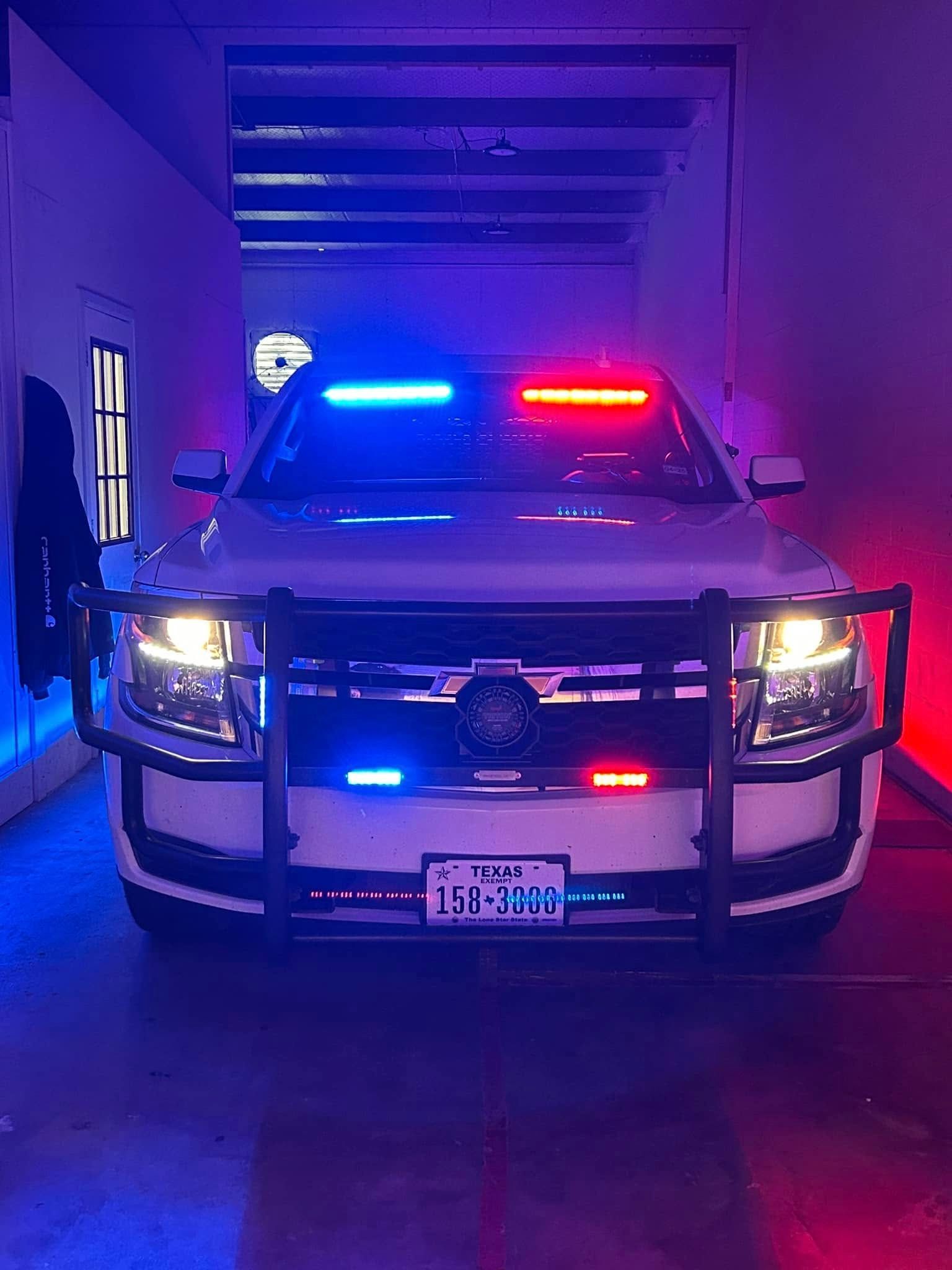 Police SUV with flashing red and blue lights, inside a building.
