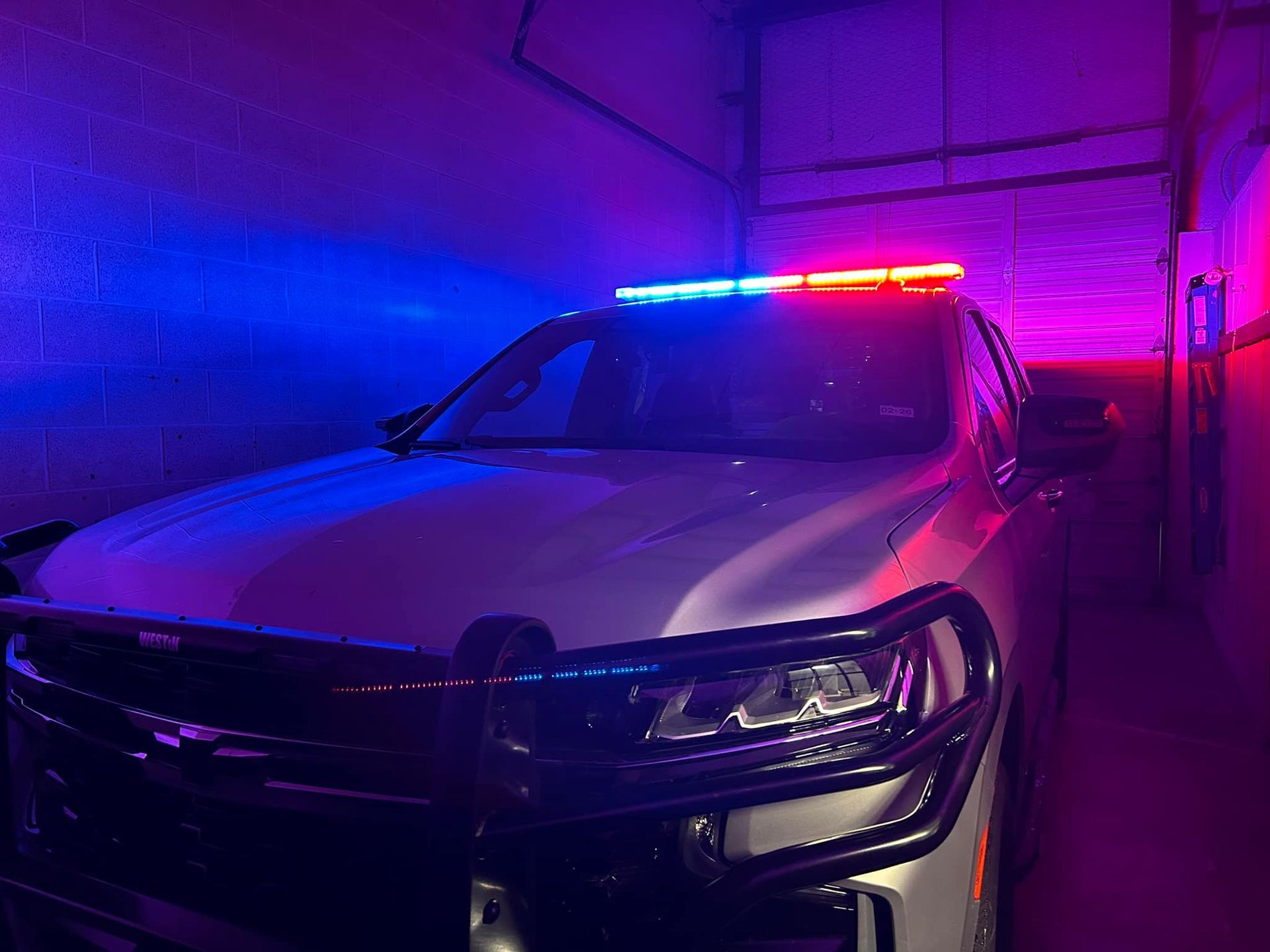 Police SUV with flashing red and blue lights in a garage.