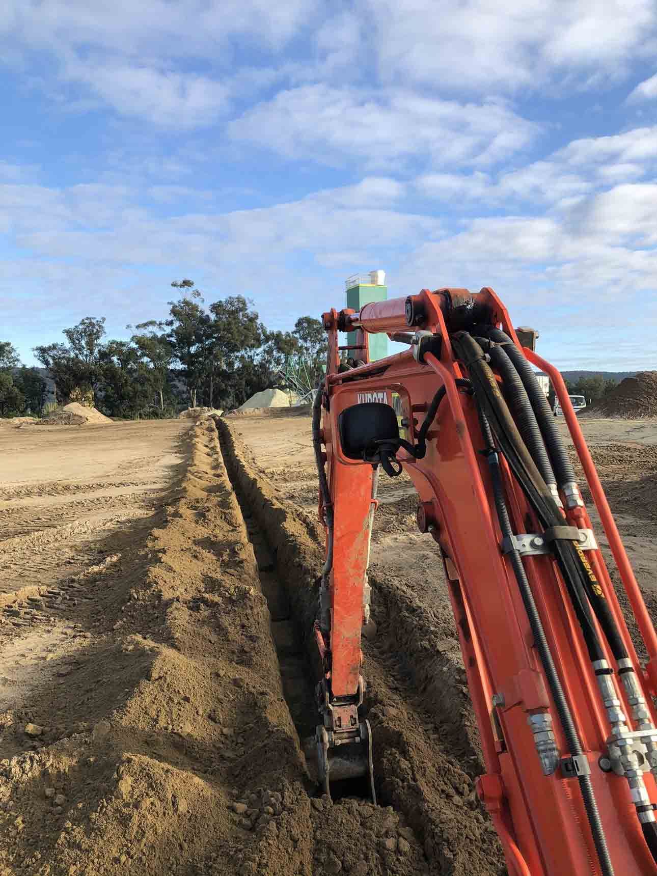 An orange excavator is digging a trench