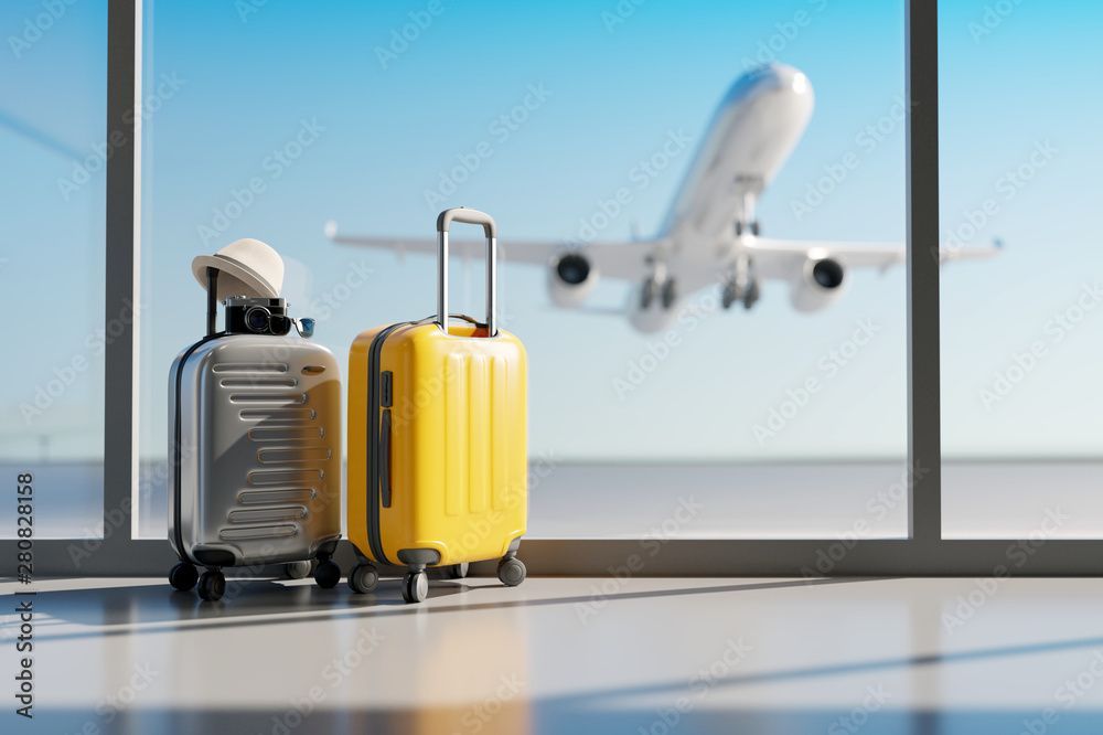 Two suitcases in an airport with a plane taking off in the background.