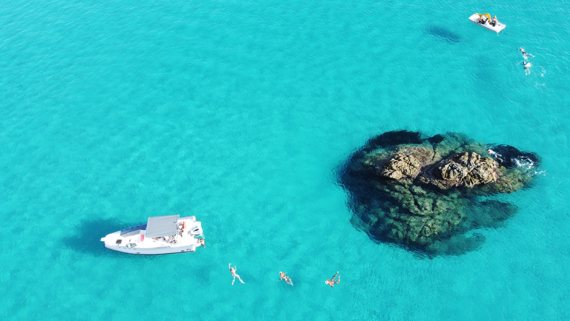 Couple kissing on a boat on a waterway with houses in the background. The woman has orange braids, the man wears a hat.