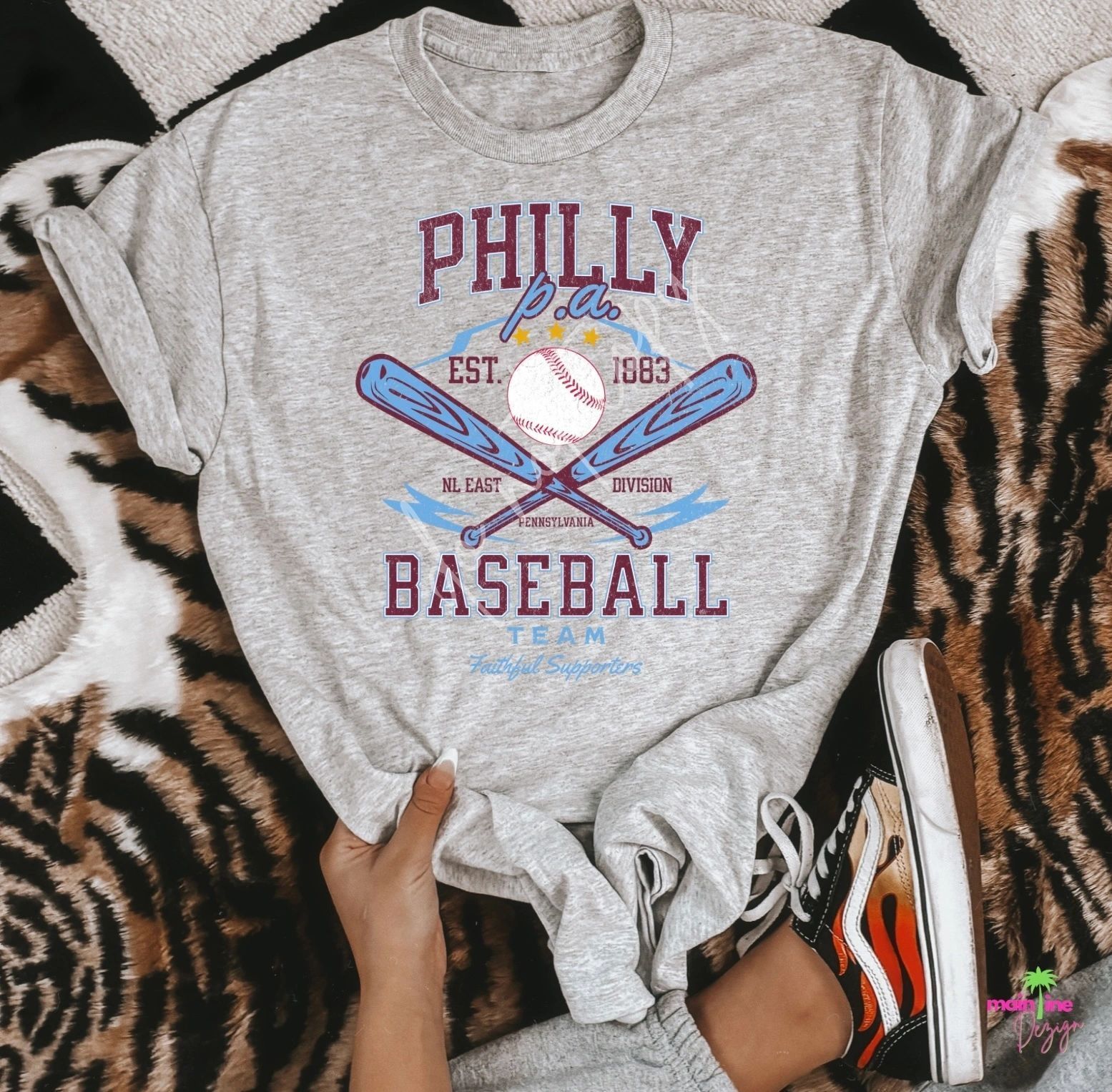 A person is holding a gray t-shirt that says philly baseball team