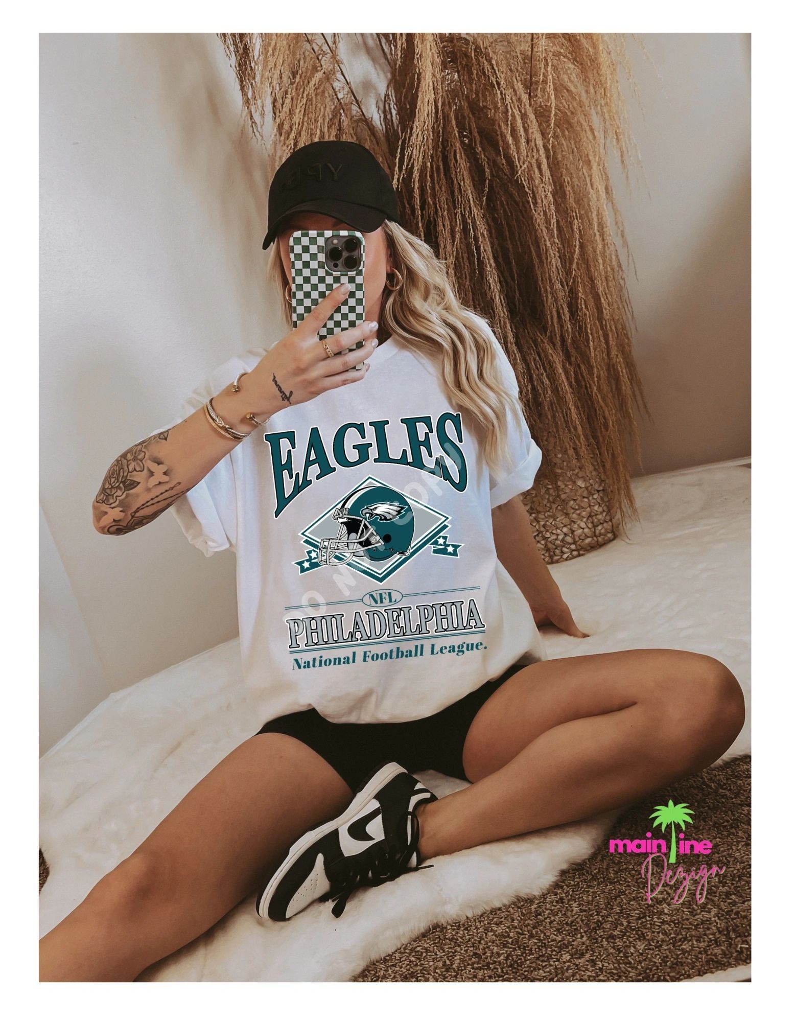A woman is taking a selfie with her phone while wearing a eagles t-shirt.