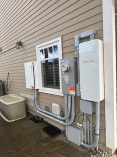 A white electrical box is sitting on the side of a house next to a window.