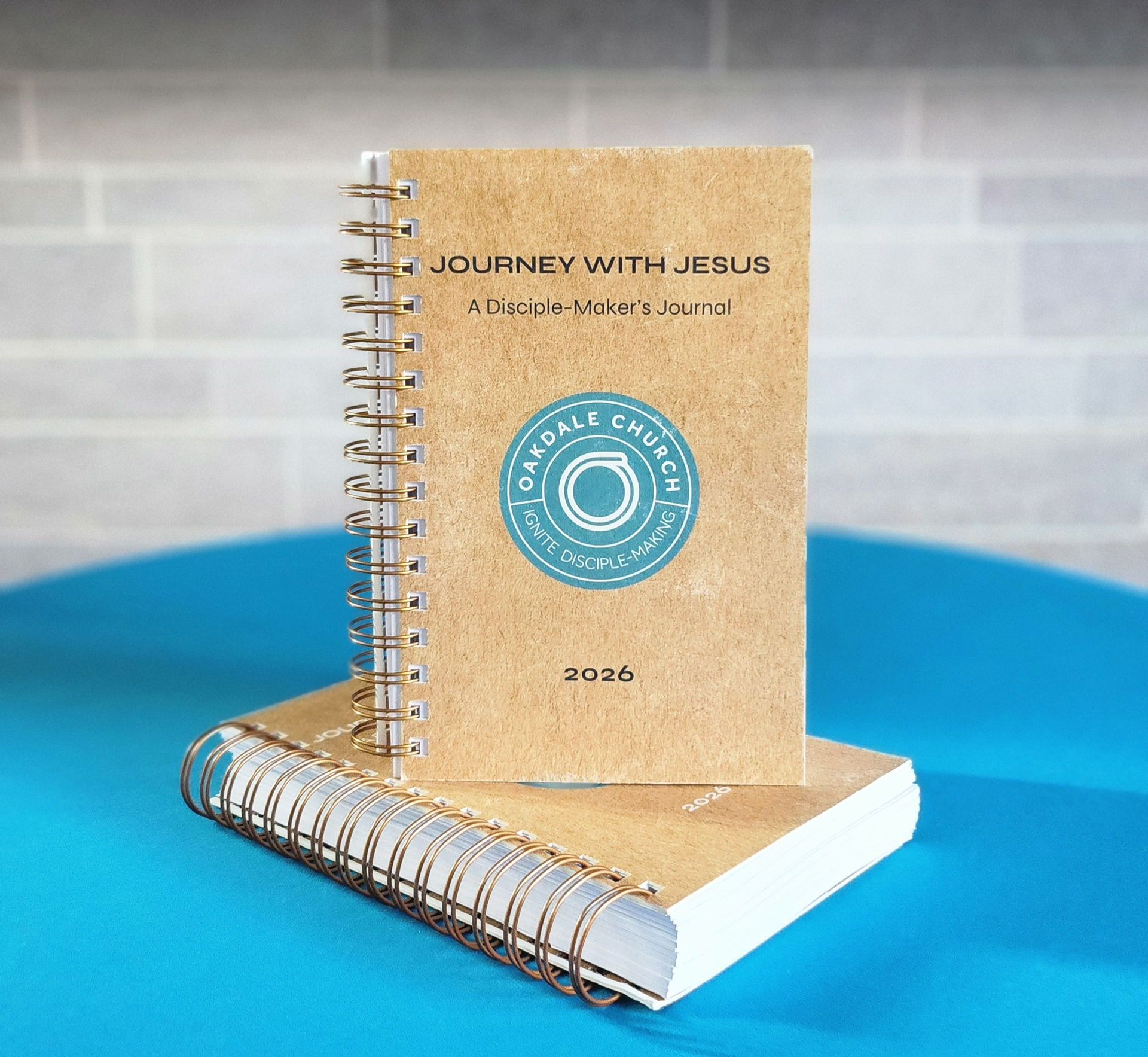 Two spiral-bound journals on a blue surface. One journal is standing upright, showing its cover: 