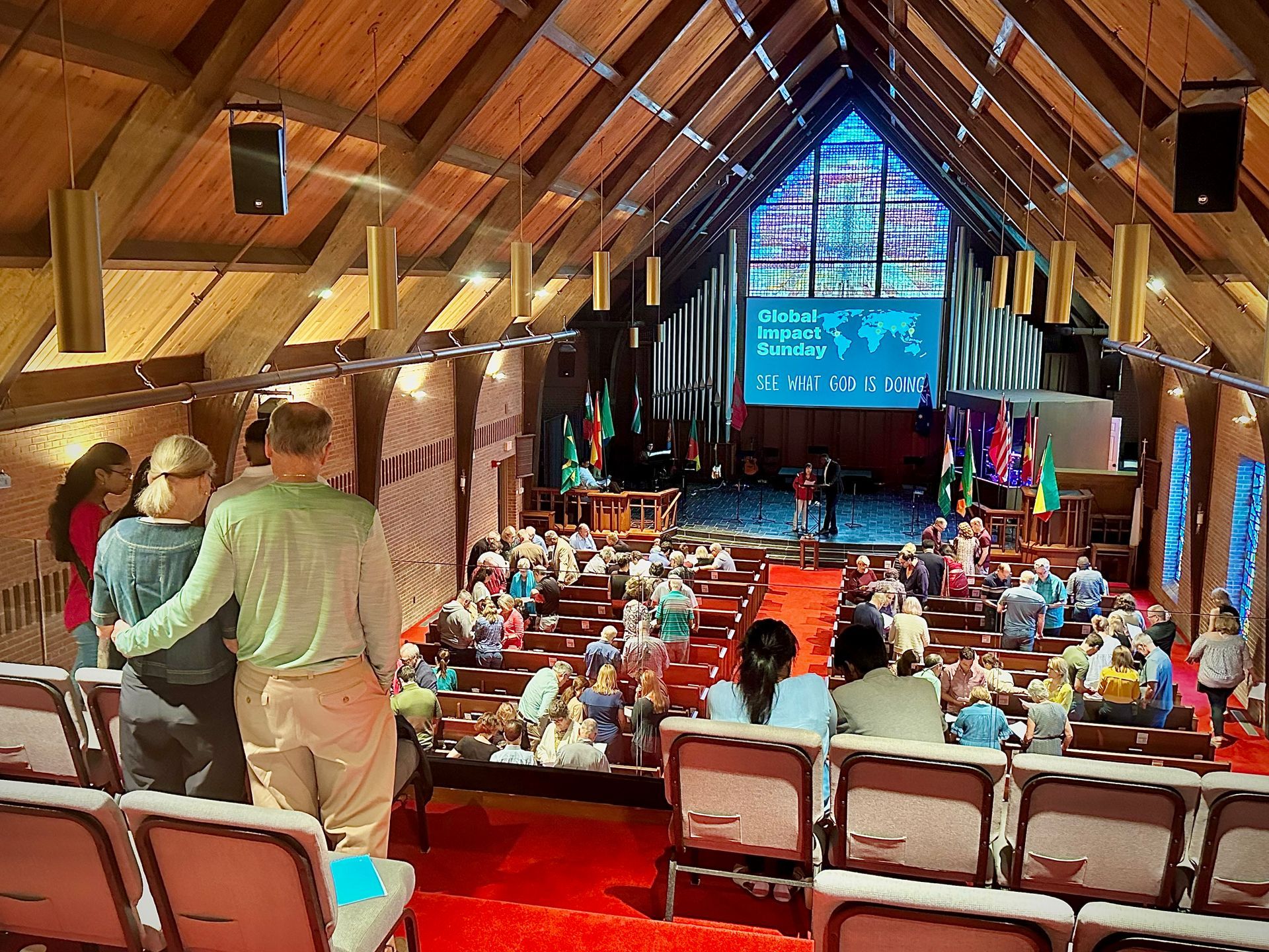 A group of people are sitting in a church with a large screen on the wall.