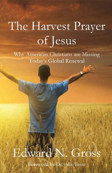 A man is standing in a field with his arms outstretched.