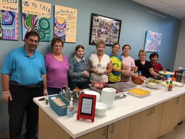 A group of people standing around a table with food on it