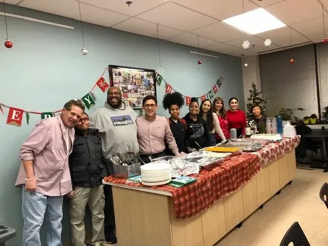 A group of people are posing for a picture in front of a long table.