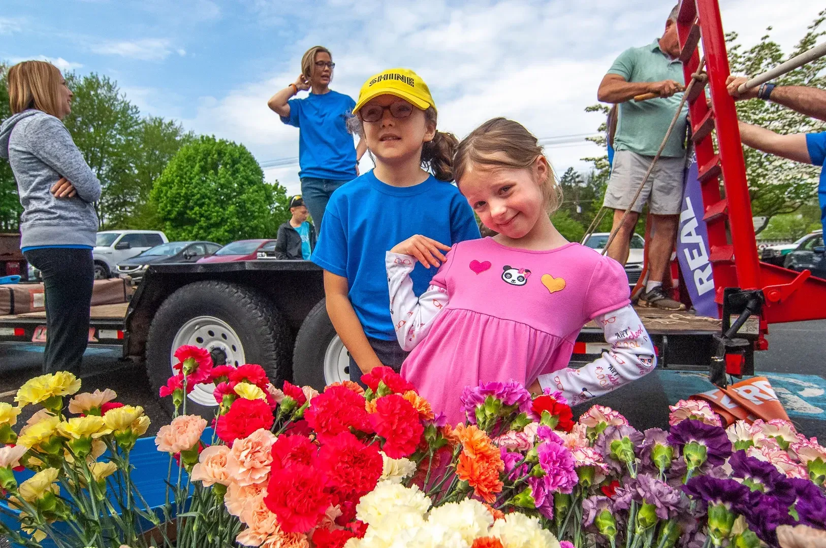 A boy and a girl are standing next to a bunch of flowers.