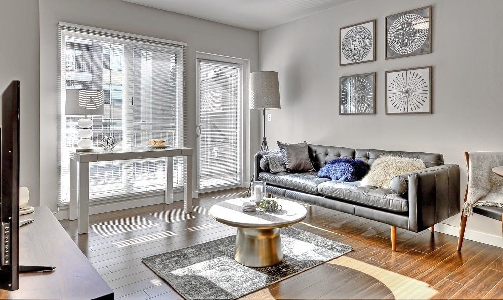 Living room with a gray leather couch, round coffee table, and framed art on the wall.
