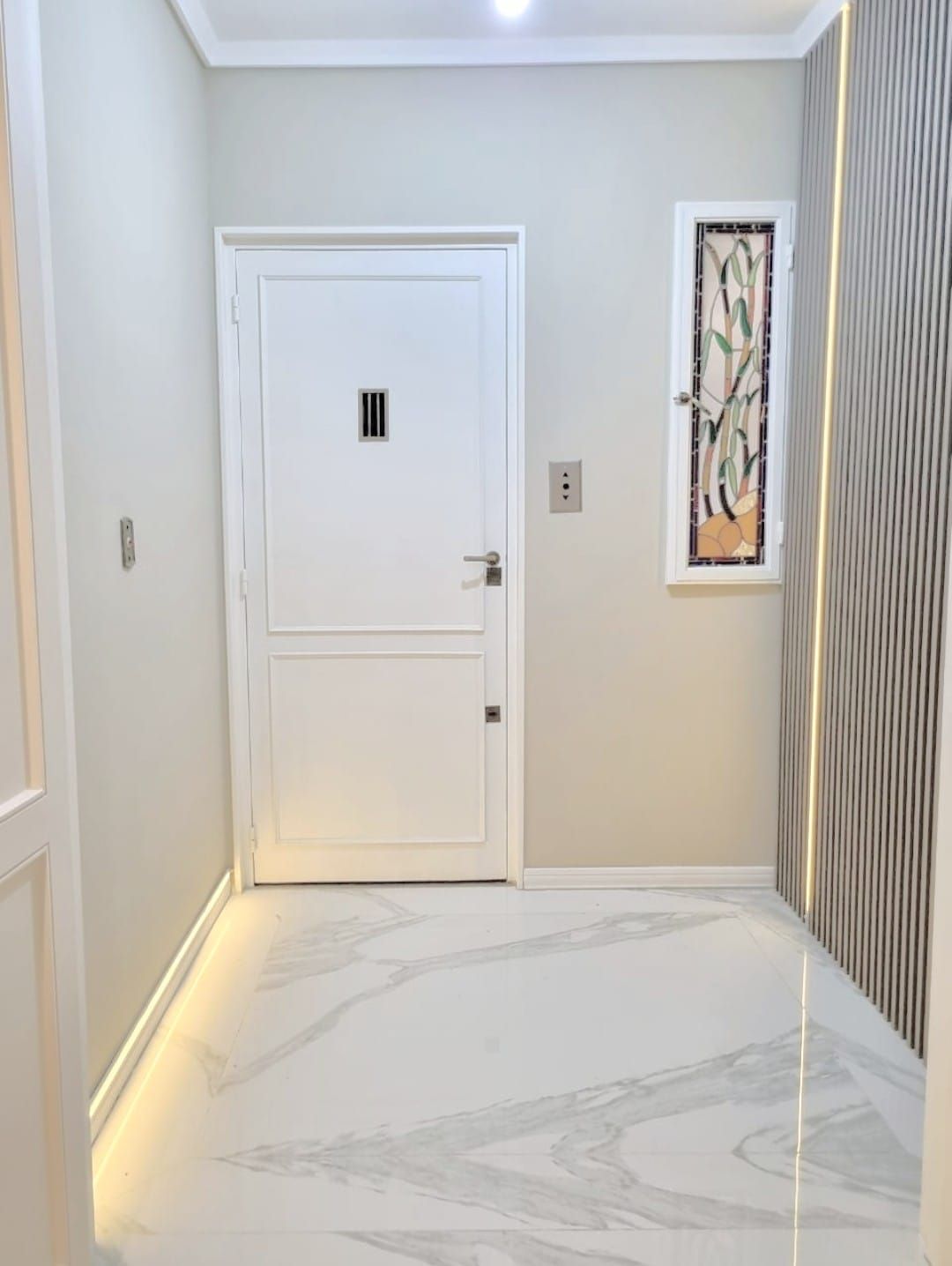 Un pasillo con una puerta y una ventana en una casa.