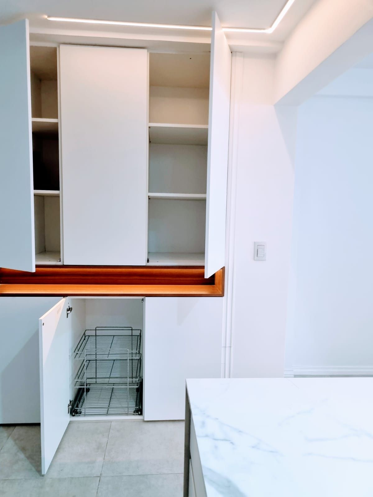 Una cocina con gabinetes blancos y encimera de mármol.