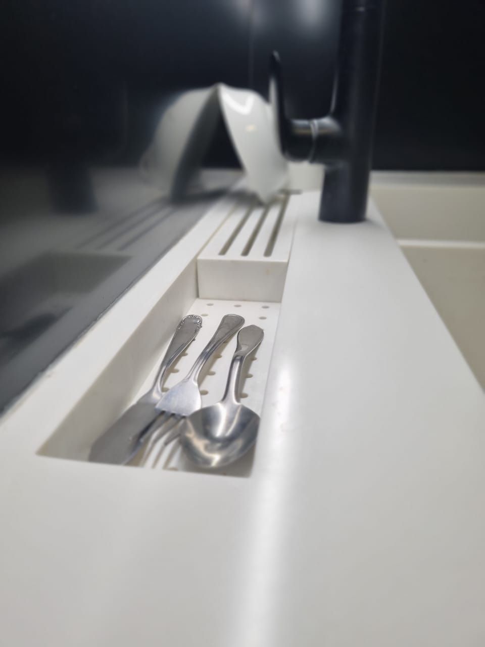 Una encimera de cocina con un fregadero y utensilios.