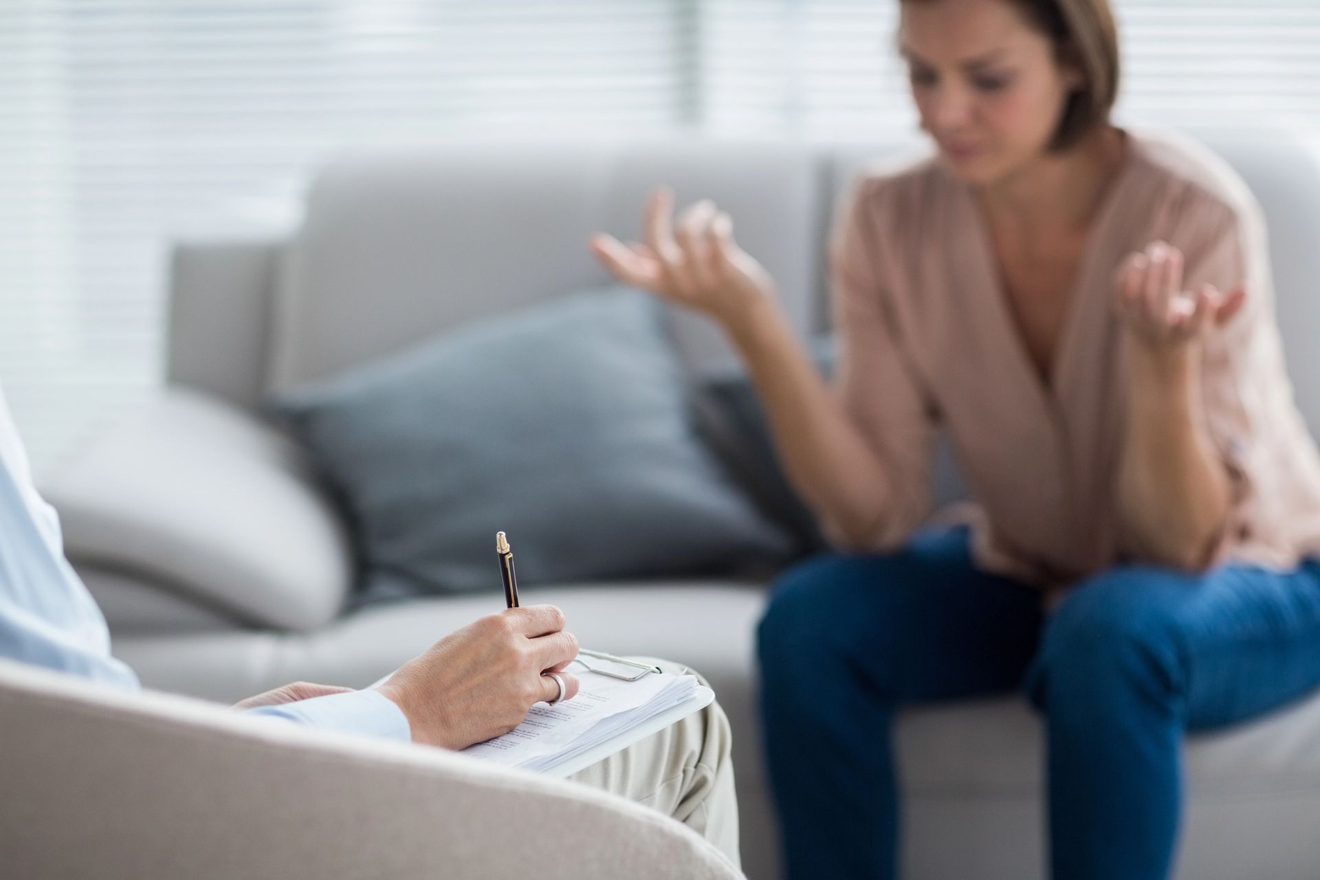 A woman is sitting on a couch talking to a psychologist.