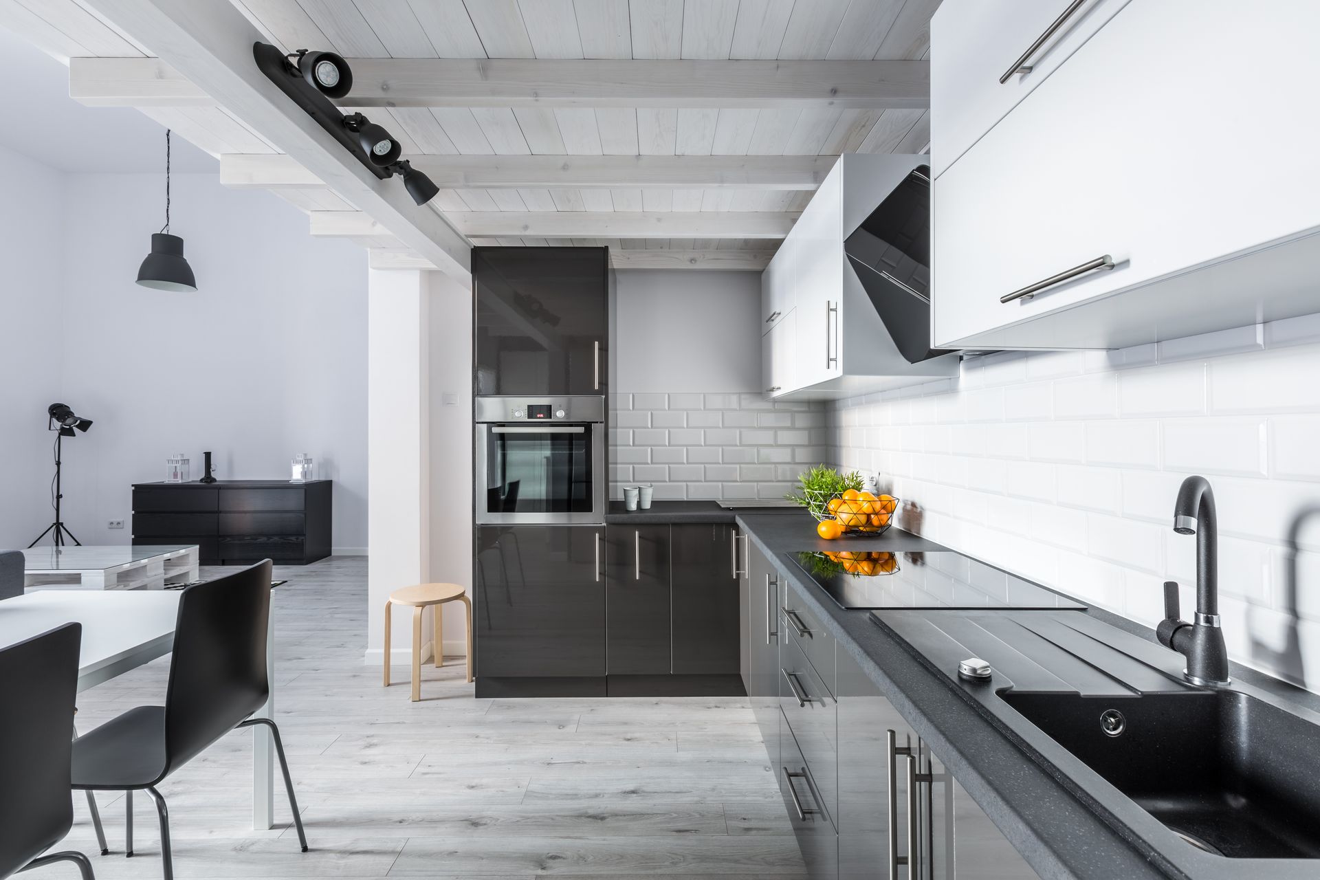 Modern kitchen with gray and white cabinets, black countertop, and dining table.