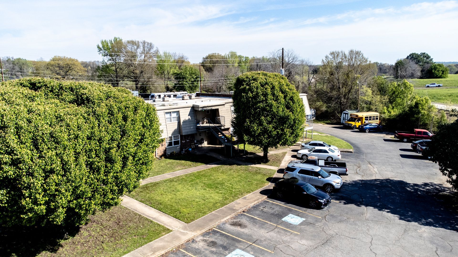 An aerial view of a parking lot with cars parked in front of a building.